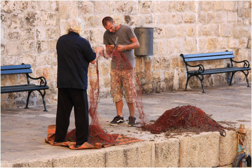 Fischer reparieren ihre Netze am Kai des inneren Hafens. / Fishermen repair their nets on the quayside of the inner harbour.